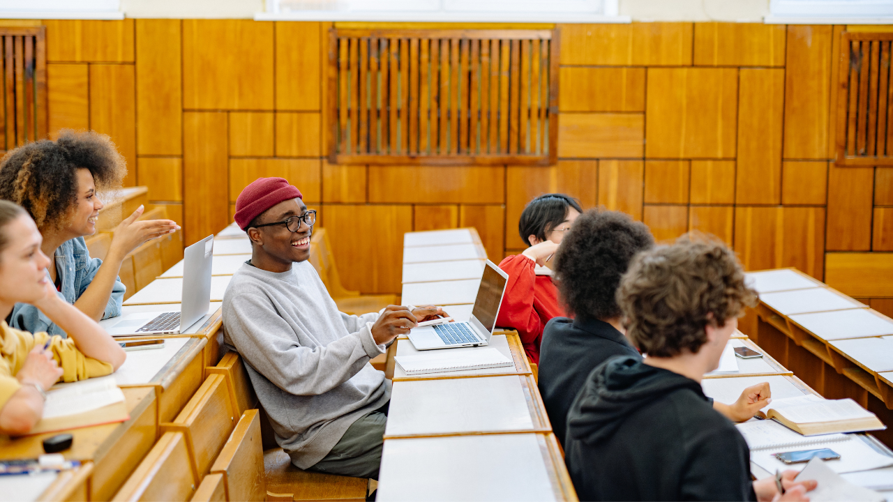 Diverse university students collaborating with laptops in a wood-paneled lecture hall